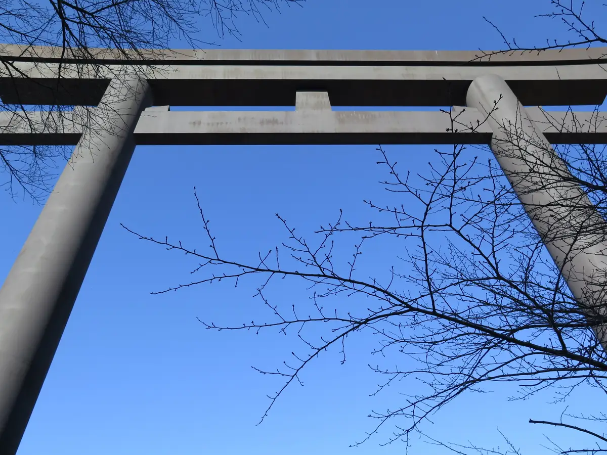 Looking up at the giant steel torii gate at Oyunohara against a blue sky