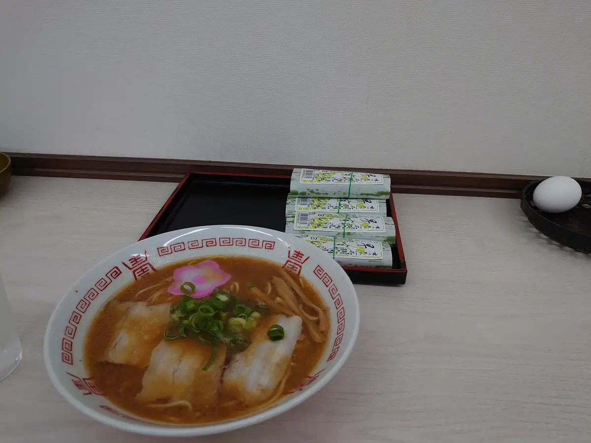 店內吧台上的一碗和歌山拉麵，後方托盤上擺著盒裝早壽司與一顆水煮蛋
